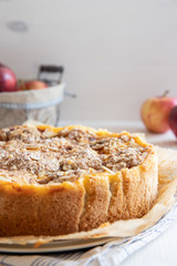Bratapfelkuchen mit Äpfeln und Mandelblättchen auf hellem weißen Holzgrund
