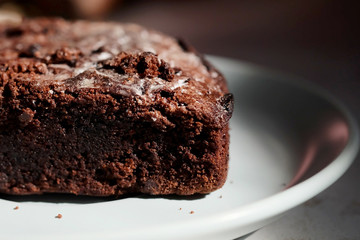 Homemade chocolate cake in white dish and sunlight and space for write wording, unhealthy sweet caused dangerous chronic illness such as diabetes, popular sweet sold in restaurant.