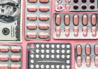 white and pink pills in blister with money dollar on a pink background, medicine flat lay