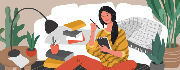 A girl is sitting on the floor surrounded by a laptop, books and papers and writing in note. Woman studying or preparing for exams at home. Teen student studying hard In scandinavian