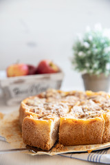 Bratapfelkuchen mit Äpfeln und Mandelblättchen auf hellem weißen Holzgrund