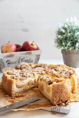 Bratapfelkuchen mit Äpfeln und Mandelblättchen auf hellem weißen Holzgrund