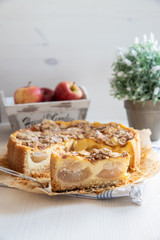 Bratapfelkuchen mit Äpfeln und Mandelblättchen auf hellem weißen Holzgrund