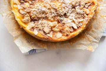 Bratapfelkuchen mit Äpfeln und Mandelblättchen auf hellem weißen Holzgrund