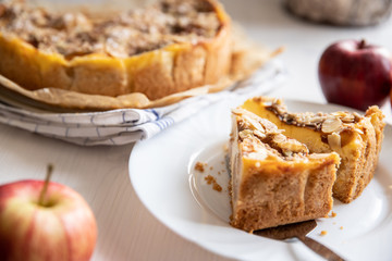 Bratapfelkuchen mit Äpfeln und Mandelblättchen auf hellem weißen Holzgrund