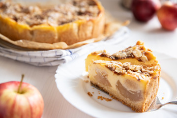 Bratapfelkuchen mit Äpfeln und Mandelblättchen auf hellem weißen Holzgrund