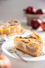 Bratapfelkuchen mit Äpfeln und Mandelblättchen auf hellem weißen Holzgrund