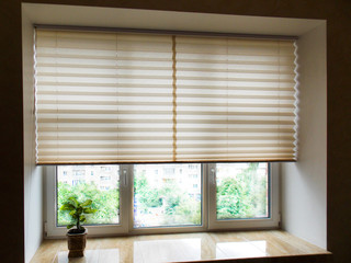 Pleated blinds XL beige color, with 50mm fold closeup in the window opening in the interior. Home blinds - modern bottom up privacy shades half raised on apartment windows. - Powered by Adobe