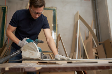 Male works on jigsaw in workshop