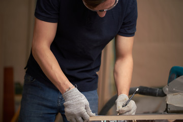 Man carpenter holds board in his workshop