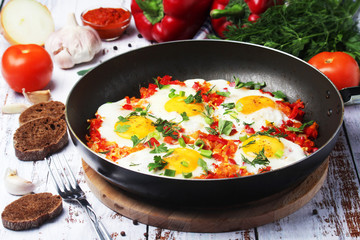 Shakshouka with five cooked eggs on top of tomato sauce in cast iron skillet	