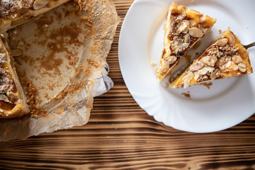 Bratapfelkuchen mit Äpfeln und Mandelblättchen auf dunklen Holzgrund