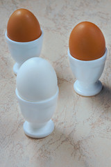 fresh chicken eggs in ceramic cups on a wooden background. Healthy eating concept