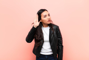 young latin pretty woman looking serious and curious, listening, trying to hear a secret...