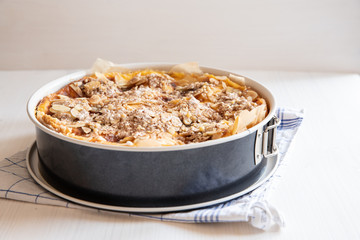 ganzer Bratapfelkuchen in einer Backform auf hellem weißen Holzgrund mit Küchentuch