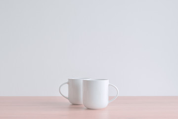 Two white coffee cups on the table in morning