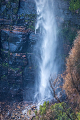 Fototapeta na wymiar Waterfall tumbling down onto boulders at its base