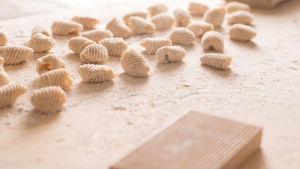 Fototapeta na wymiar Close up of homemade vegan gnocchi pasta with wholemeal flour on the wooden chopping board with back light morning sunlight bokeh effect, traditional Italian pasta
