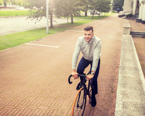 lifestyle, transport and people concept - young man riding bicycle on city street