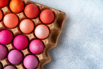 Several Easter eggs in different shades of pink in eggbox