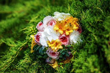 Obraz na płótnie Canvas Top view of bridal bouquet with white, yellow and rose flowers on grass in summer wedding day. Outdoor wedding decor. Idea for wedding bouquet picture.