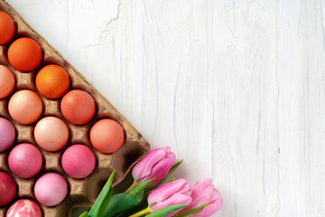 Painted Easter eggs in an eggbox with fresh tulips close up