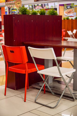 Available metal chair and table in restaurant, canteen or cafe. Interior of public dining area with colourful plastic chairs and tables. Modern, simple, colorful and creative cafe interior.