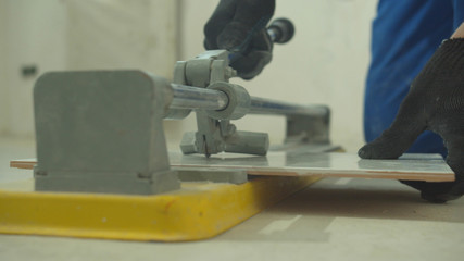 Slow motion, man in protective gloves cuts a tile