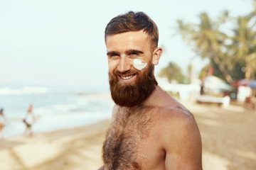 Handsome Man with beard, In Sunglasses Sunbathing With Sunscreen Lotion Body In Summer. Male Fitness Model Tanning Using Solar Block Cream For Healthy Tan. Skincare. Sun Skin Protection