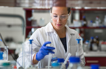 Female researcher carrying out scientific research in a lab (shallow DOF; color toned image)