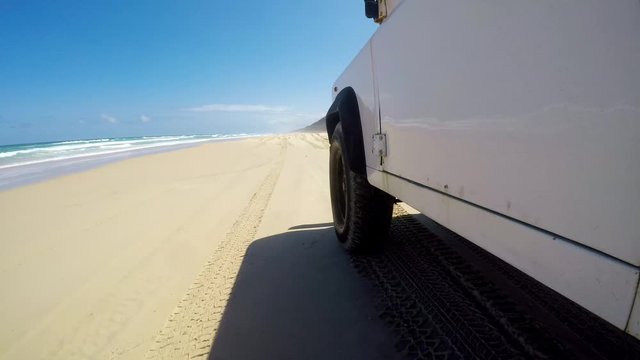 Stabilized action low angle footage of an old four-wheel drive off-road vehicle driving on famous Seventy Five Mile Beach (75 Mile Beach) on Fraser Island off the coast of Queensland, Australia.