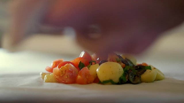 Professional chef putting pieces of gilt-head bream fish on the salad