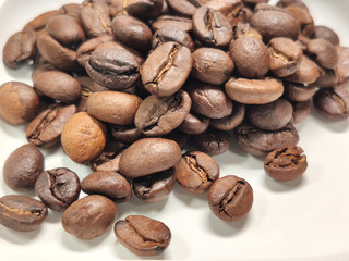 scattered roasted coffee beans on a white background close-up.