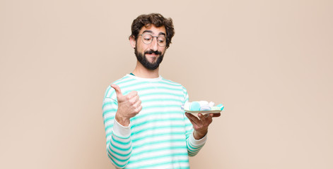 young man with macaroons against flat wall