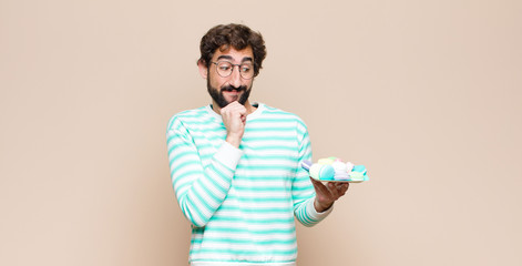 young man with macaroons against flat wall