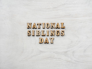Wooden letters of the alphabet in the form of the words SIBLING DAY on the table. Beautiful card. Isolated background, wooden surface. Congratulations for relatives, friends and colleagues