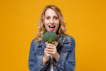 Excited young woman in denim clothes isolated on yellow orange background studio portrait. Proper...