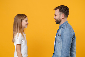 Side view of bearded man in casual clothes have fun with child baby girl. Father little kid daughter isolated on yellow background. Love family day parenthood childhood concept. Looking at each other.