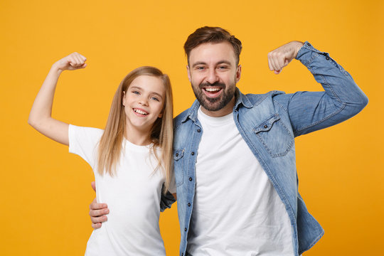Funny bearded man in casual clothes have fun with cute child baby girl. Father little kid daughter isolated on yellow background. Love family day parenthood childhood concept. Showing biceps muscles.
