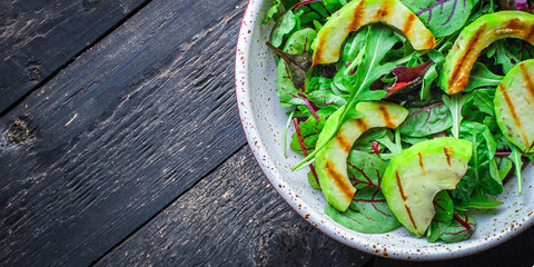 healthy salad grilled avocado and green leaves (vegetarian or diet food) menu concept background. top view. copy space
