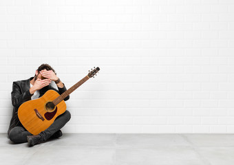 young musician man covering face with both hands saying no to the camera! refusing pictures or...