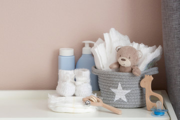 A stack of diapers, booties and baby accessories on a changing table. Copy space for text.