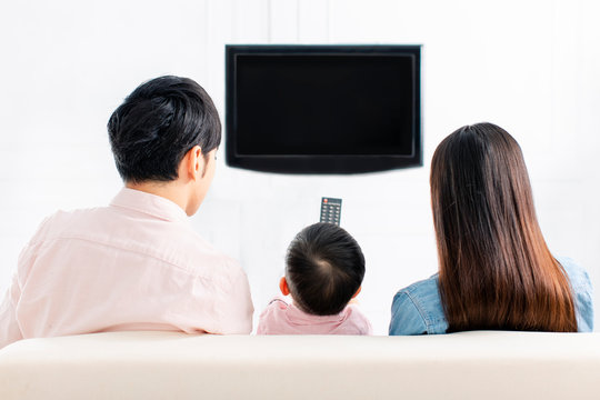 rear view of happy family watching the tv  on sofa