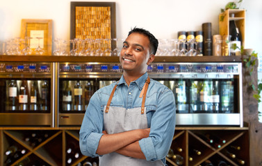 people, job and profession concept - smiling indian barman, waiter or salesman in apron over wine...