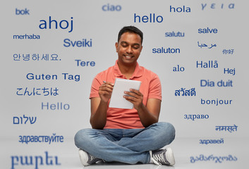 communication, learning and people concept - smiling indian man in polo shirt writing to notebook...