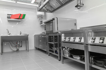 Design of the working area of the commercial cafe kitchen with stainless steel equipments, hot shop, food industry.