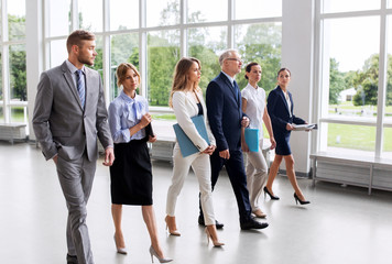 people, work and corporate concept - business team with folders walking along office building and...