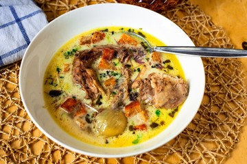 Rich thick hen soup with vegetables in white plate.
