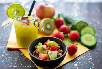 gesundes Frühstück: Müsli mit frischen Erdbeeren und Kiwis mit leckerem grünen Smoothie im Einmachglas