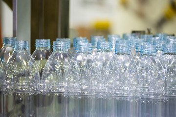 The PET bottles in the rail on the conveyor belt for filling process in the drinking water factory. The drinking water factory production process by automatic filling machine in the plant.